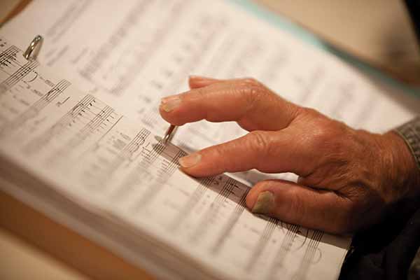 Picture of a hand following lines of music on music sheet