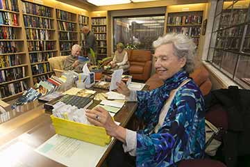 Librarian at library desk with readers in the background